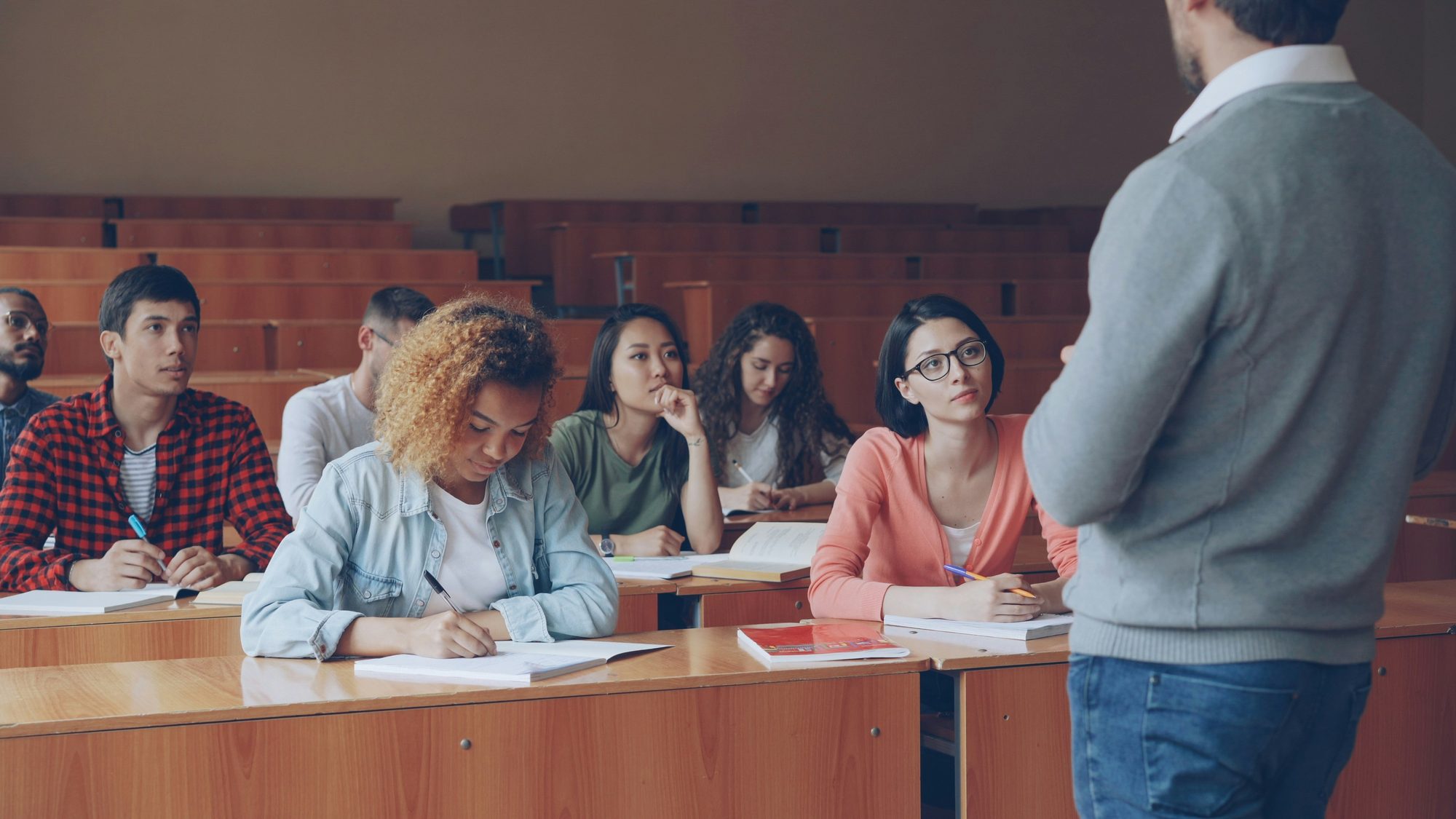 Professor ministrando aula para estudantes em auditório